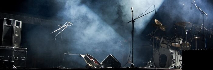 Empty stage with instruments set up and stage lights, cast in blue light and smoke.