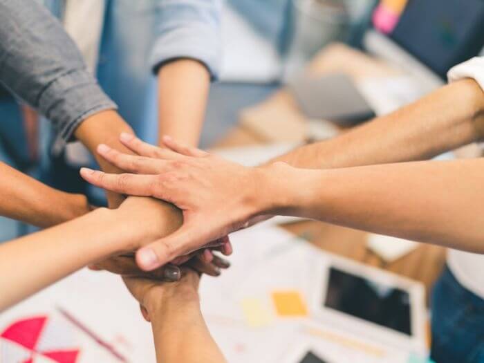 Many hands overlapping together in a circle, representing partnership and teamwork.