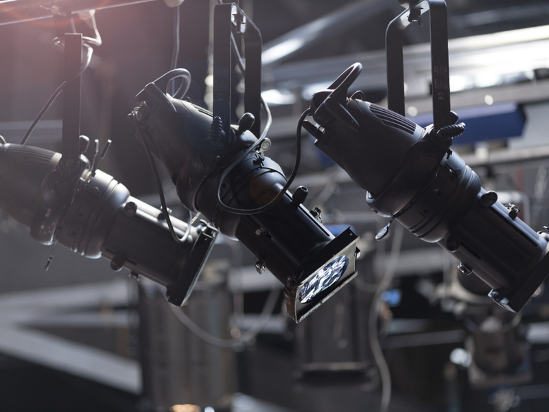 Zoom into spotlights over a theatre stage, not turned on.